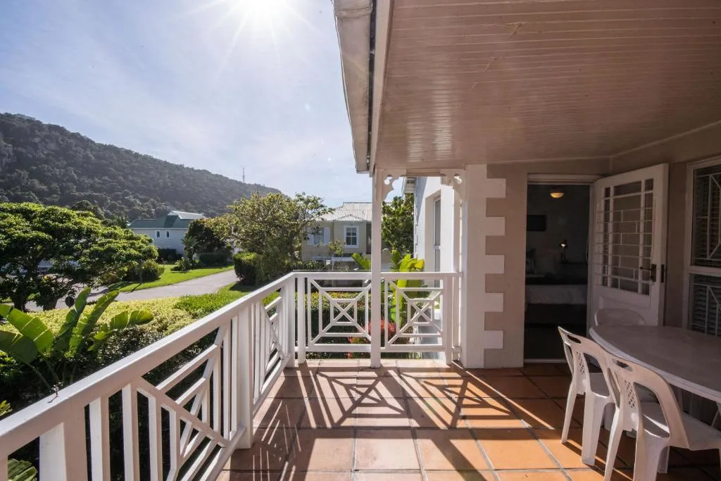 Spacious covered deck with white railings overlooking lush gardens and mountains