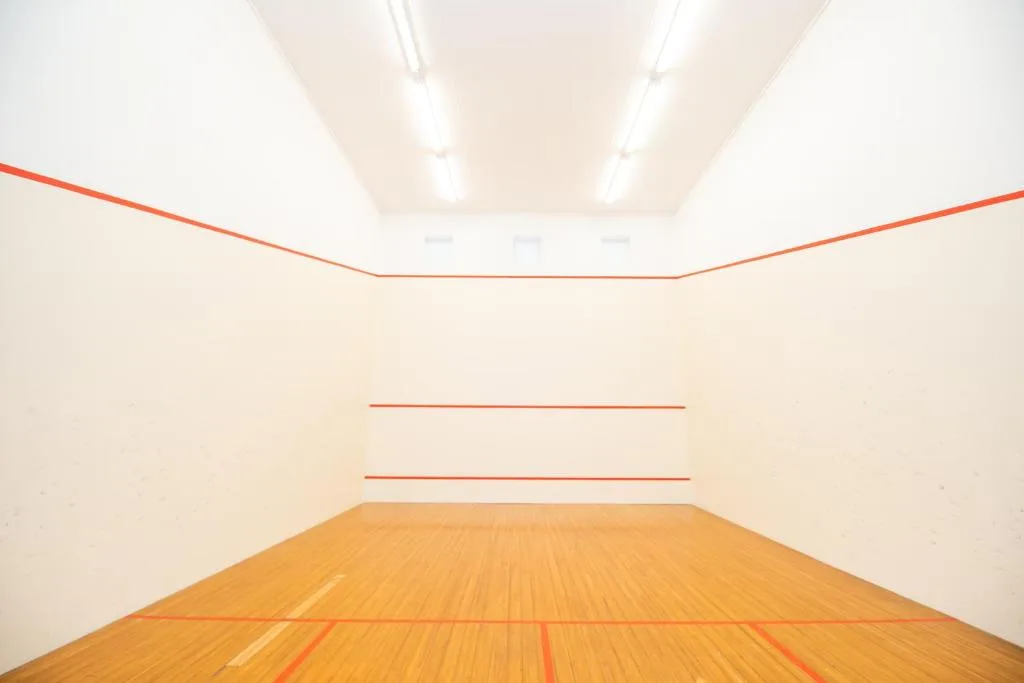 Empty squash court with wooden floor and orange court lines