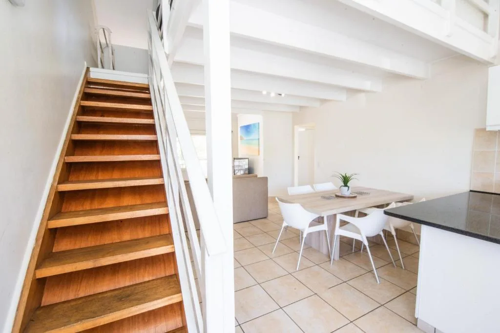 Bright dining area with wooden table and white chairs in open-plan space