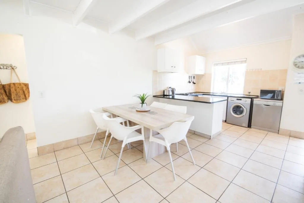 Open-plan kitchen and dining area with white table, chairs, and appliances