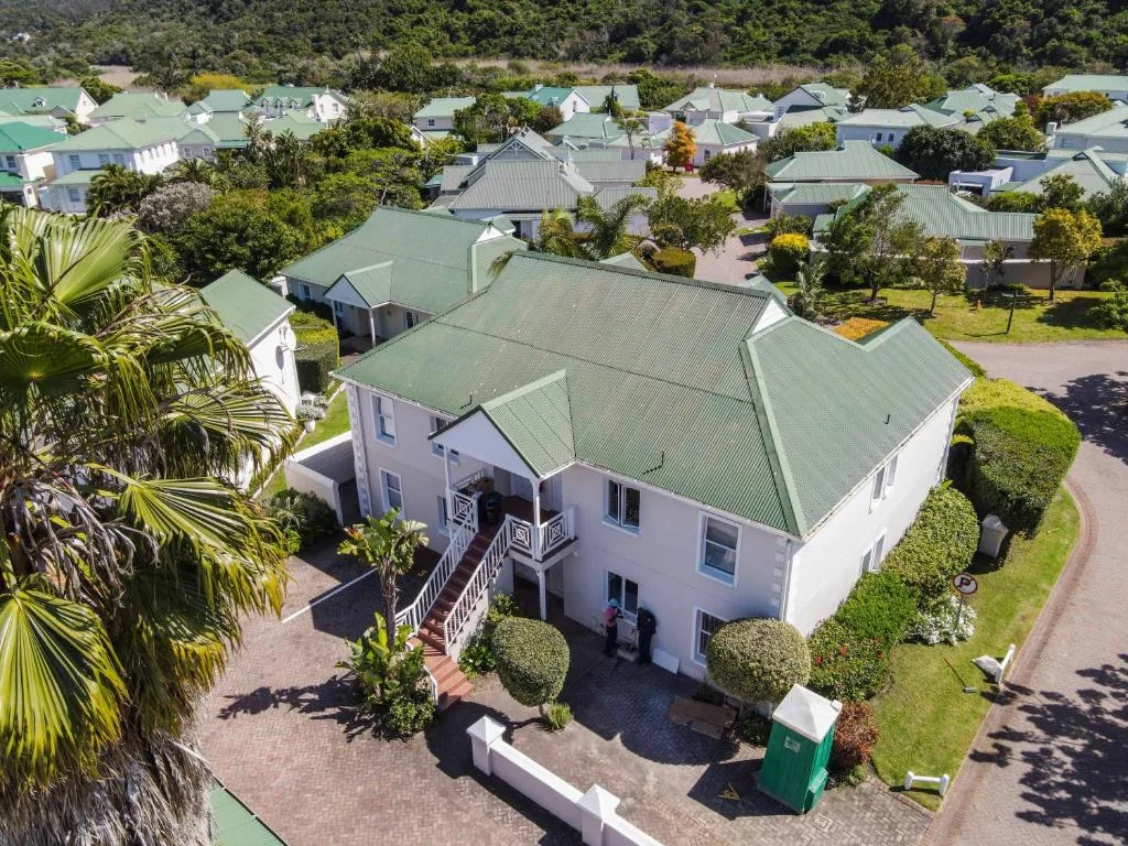 White house with green metal roof and manicured gardens in residential neighborhood