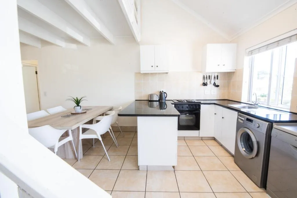 Modern kitchen with white cabinetry, black countertop, and dining area