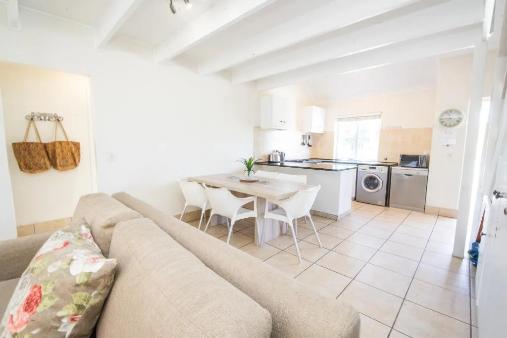 Open-plan living area with beige sofa, dining table, and kitchen visible