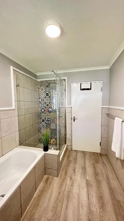 Modern bathroom with walk-in shower, bathtub, and wood-look flooring