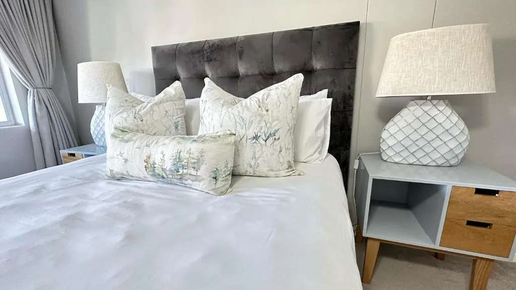 Spacious bedroom with elegant black upholstered headboard and white bedding