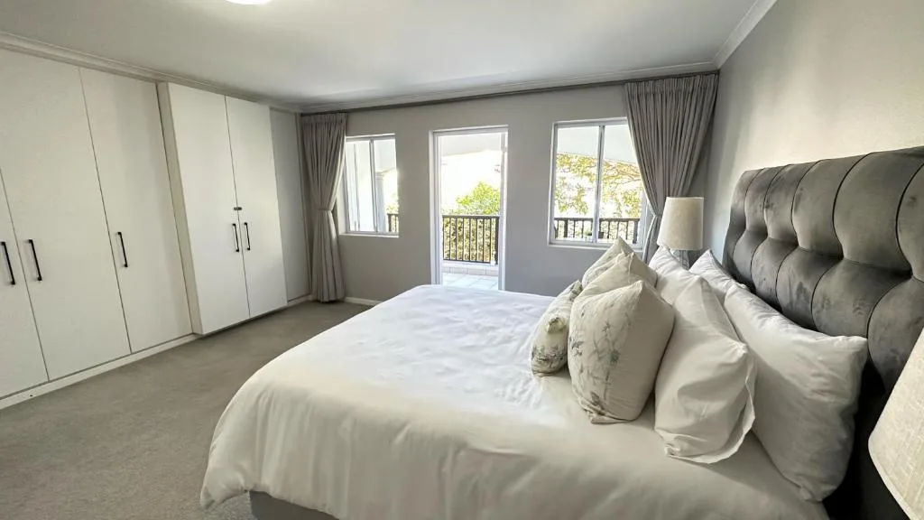Modern bedroom with queen bed, built-in wardrobes, and garden views