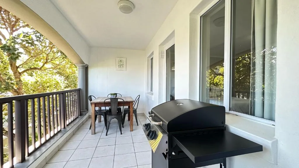 Covered patio with dining table, braai grill, and garden views