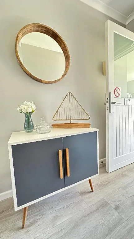 Modern entryway with wooden-framed mirror, navy cabinet, and decorative items