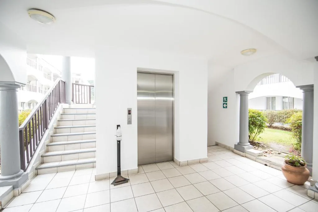 Bright common area with elevator, stairs, and arched garden entrance