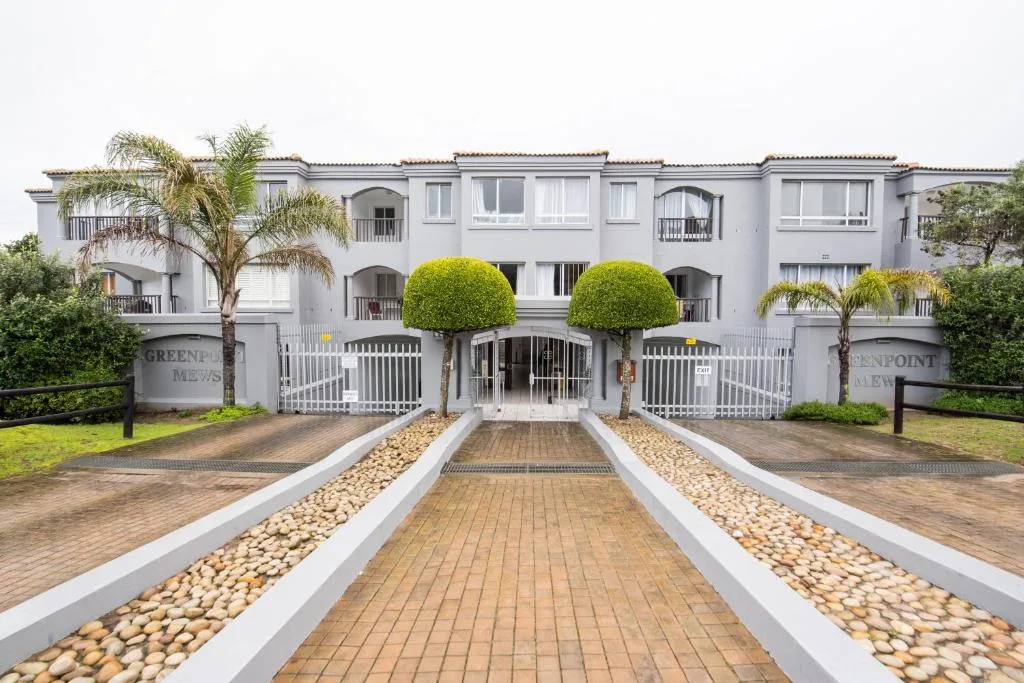 White multi-story apartment building with manicured gardens and gated entrance