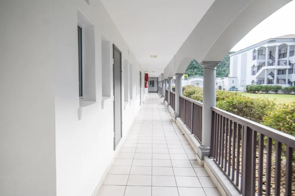 Covered walkway with white walls and dark railings along apartment building