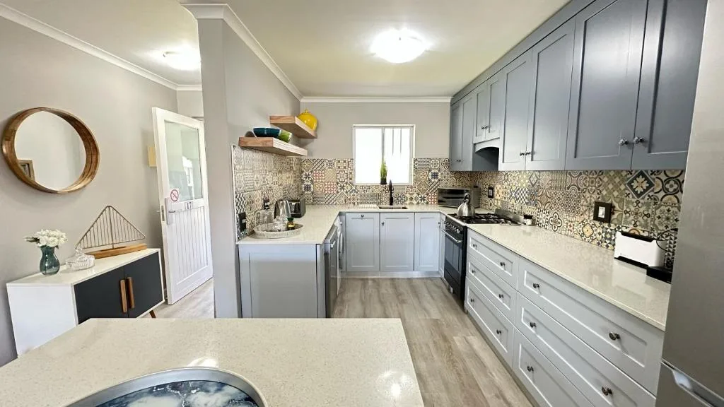 Modern kitchen with gray cabinetry, patterned tile backsplash, and stainless steel appliances