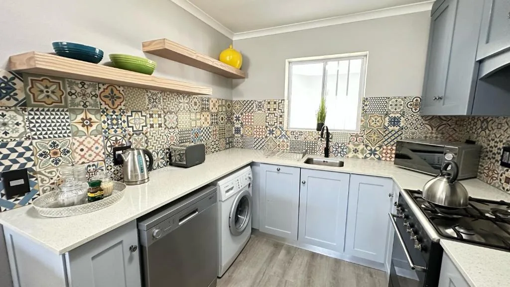 Modern kitchen with patterned tile backsplash, white cabinetry, and stainless steel appliances