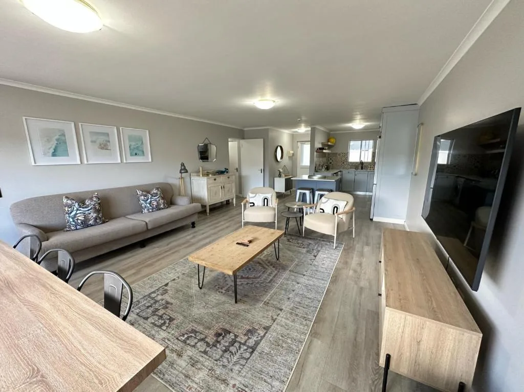 Modern open-plan lounge with grey sofa, TV, and dining area