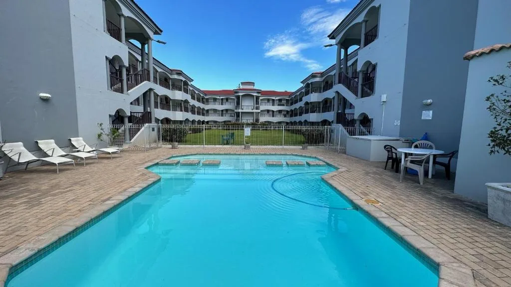 Sparkling turquoise swimming pool with loungers and surrounding apartment buildings