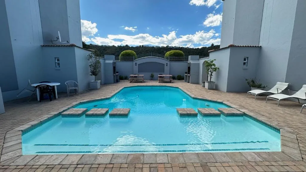 Sparkling turquoise swimming pool with loungers and white courtyard walls