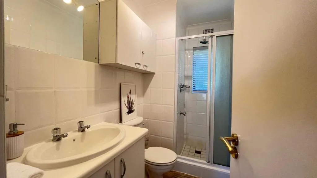 Modern bathroom with curved sink, toilet, and enclosed shower cubicle