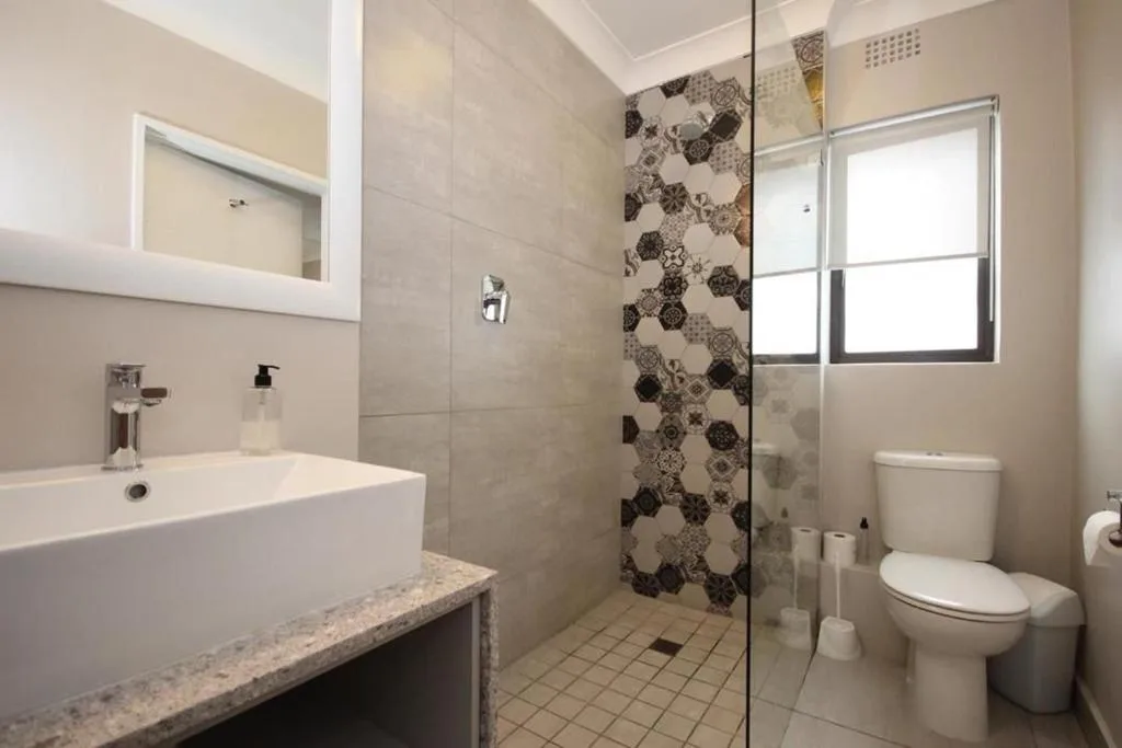 Modern bathroom with vanity sink, walk-in shower, and toilet