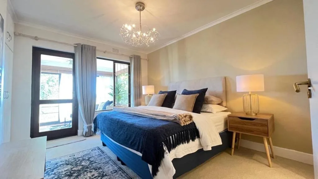 Elegant bedroom with blue bedding, crystal chandelier, and garden view doors