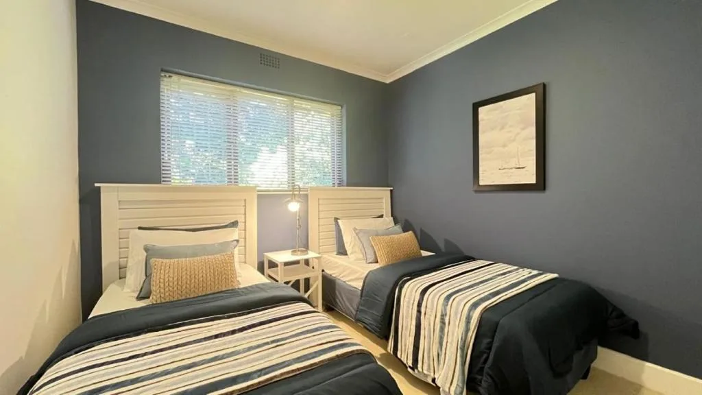 Twin bedroom with striped bedding, wooden headboards, and natural light from windows