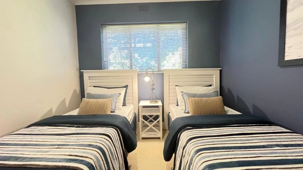 Twin bedroom with nautical bedding and view through horizontal blinds