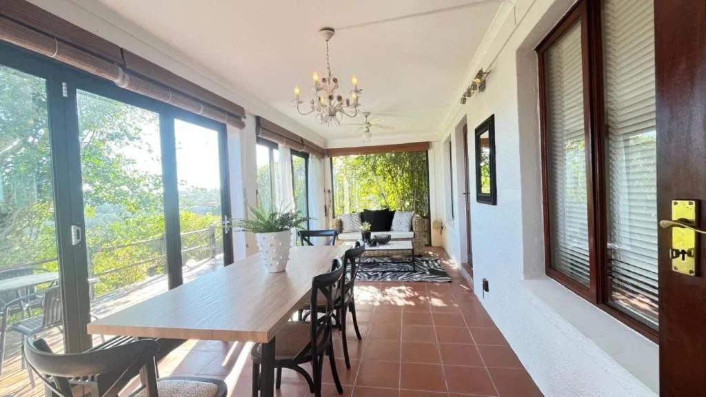 Covered veranda with dining table, lounge seating, and garden views