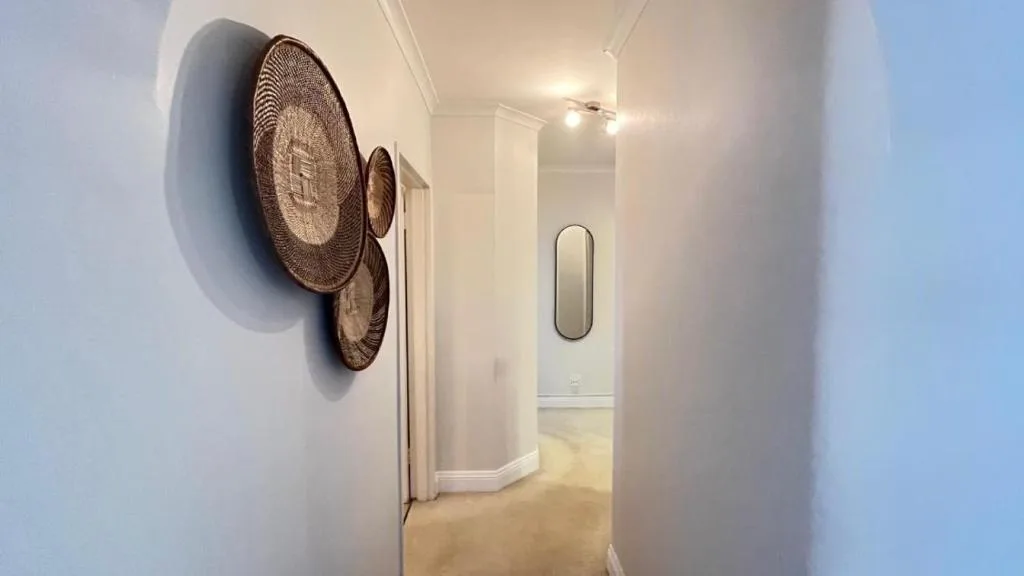Hallway with woven circular wall art and modern mirror decoration