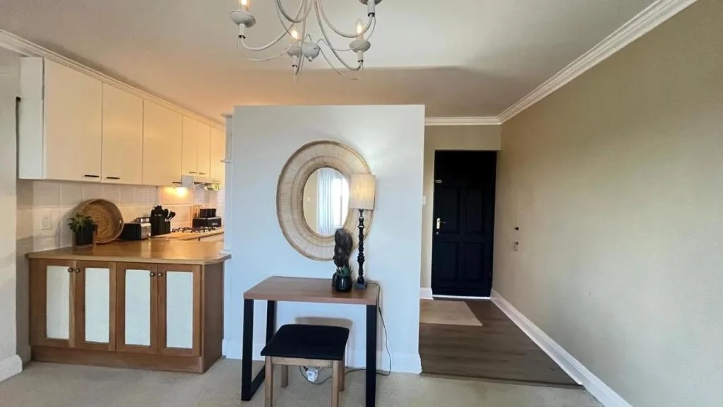 Open-plan apartment interior with kitchen, decorative mirror, and entrance hallway