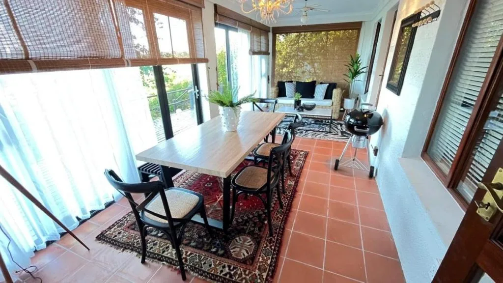 Dining table with black chairs and lounge seating visible beyond