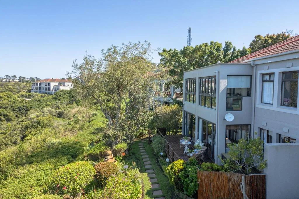 Modern white apartment building with garden and lush green surroundings