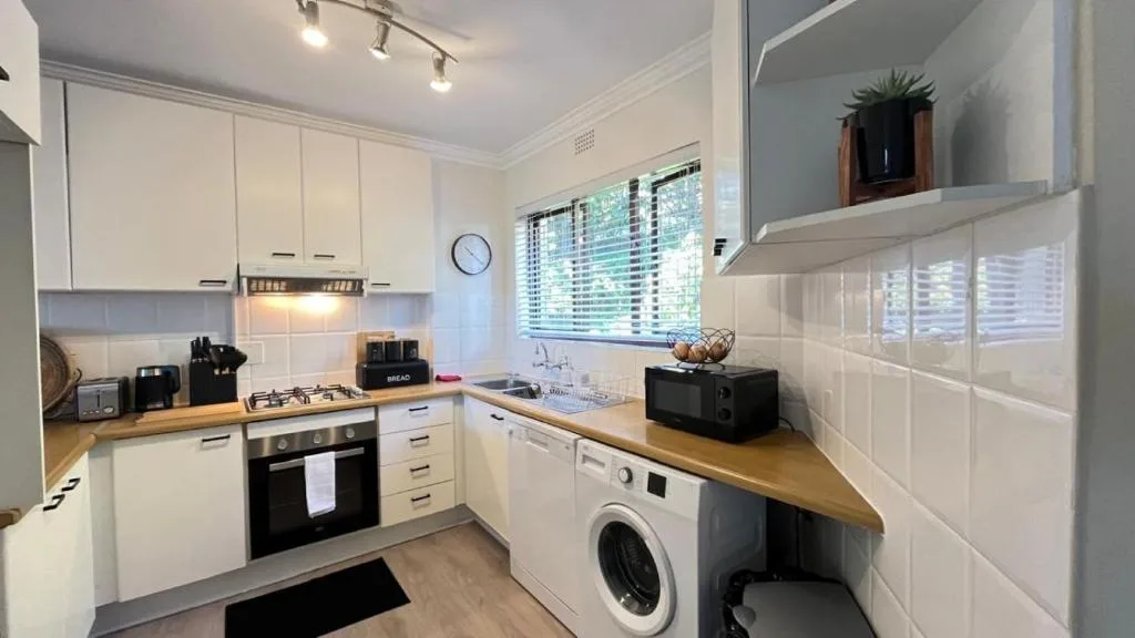 Modern kitchen with white cabinetry, wooden countertops, and stainless steel appliances