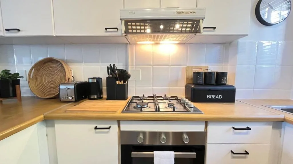 Modern kitchen with gas cooktop, white cabinetry, and wooden countertops