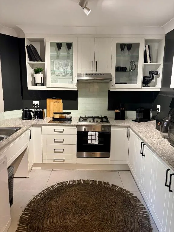 Modern white kitchen with black accents, gas cooktop, and stainless steel appliances