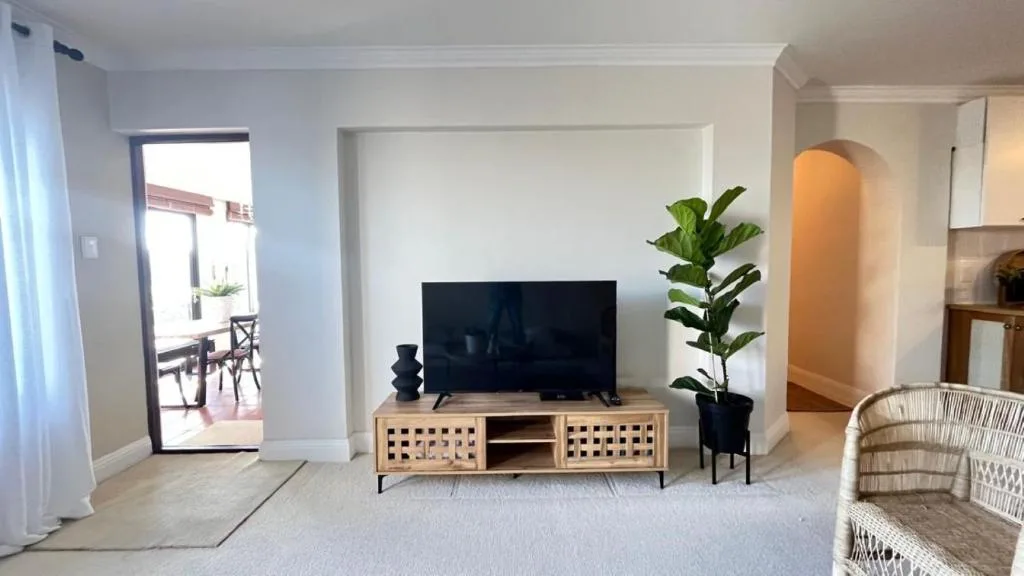 Bright living room with TV on wooden stand and potted plant decor
