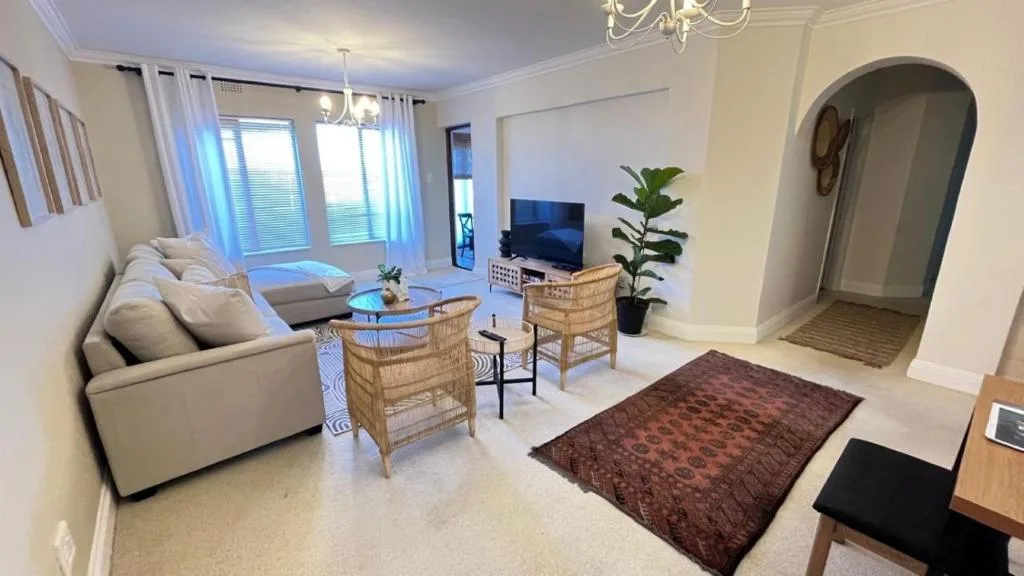 Bright open-plan living room with cream sofa, TV, and ocean-view windows