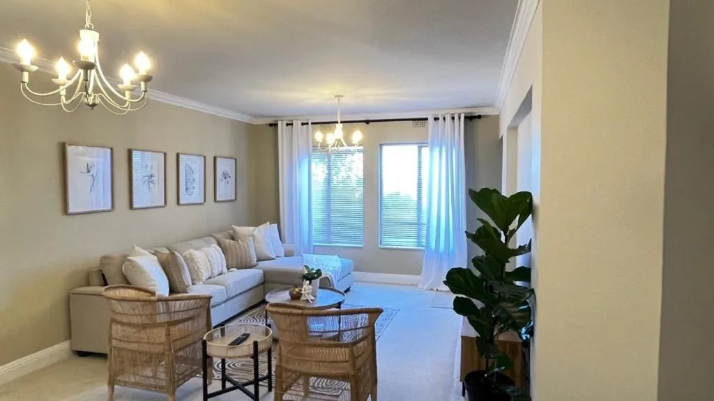 Bright living room with cream sofa, wicker chairs, and natural light from doors