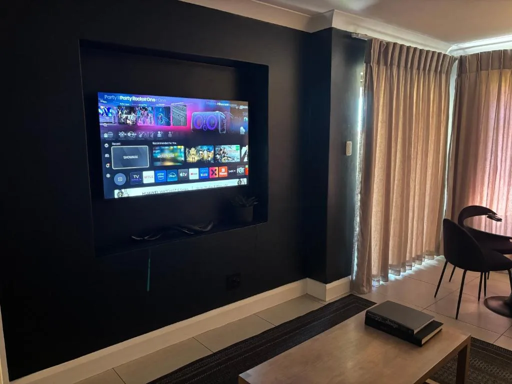 Modern lounge with wall-mounted TV displaying streaming service menu