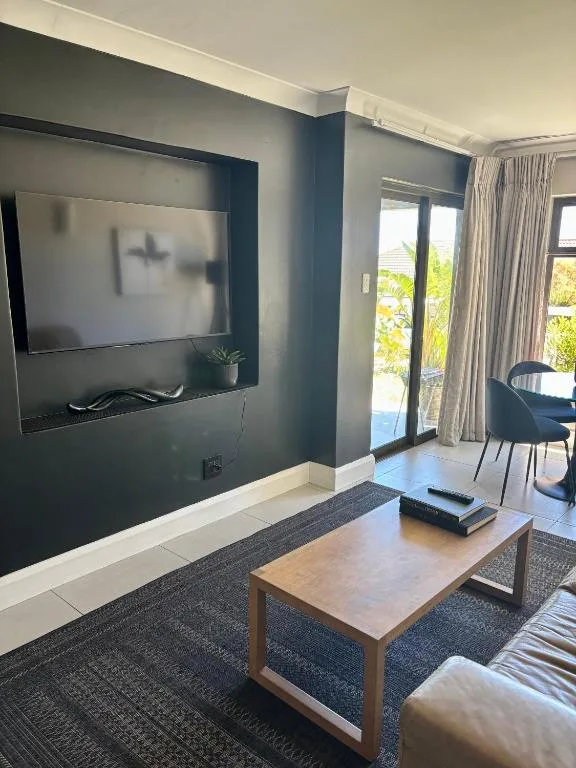 Modern living room with wall-mounted TV, wooden coffee table, and deck doors