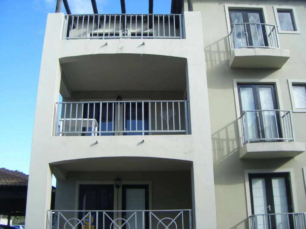 Modern white apartment building with multiple balconies and metal railings