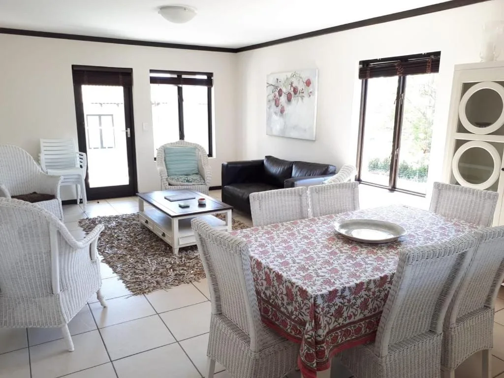 Open-plan lounge and dining area with wicker furniture and black sofa