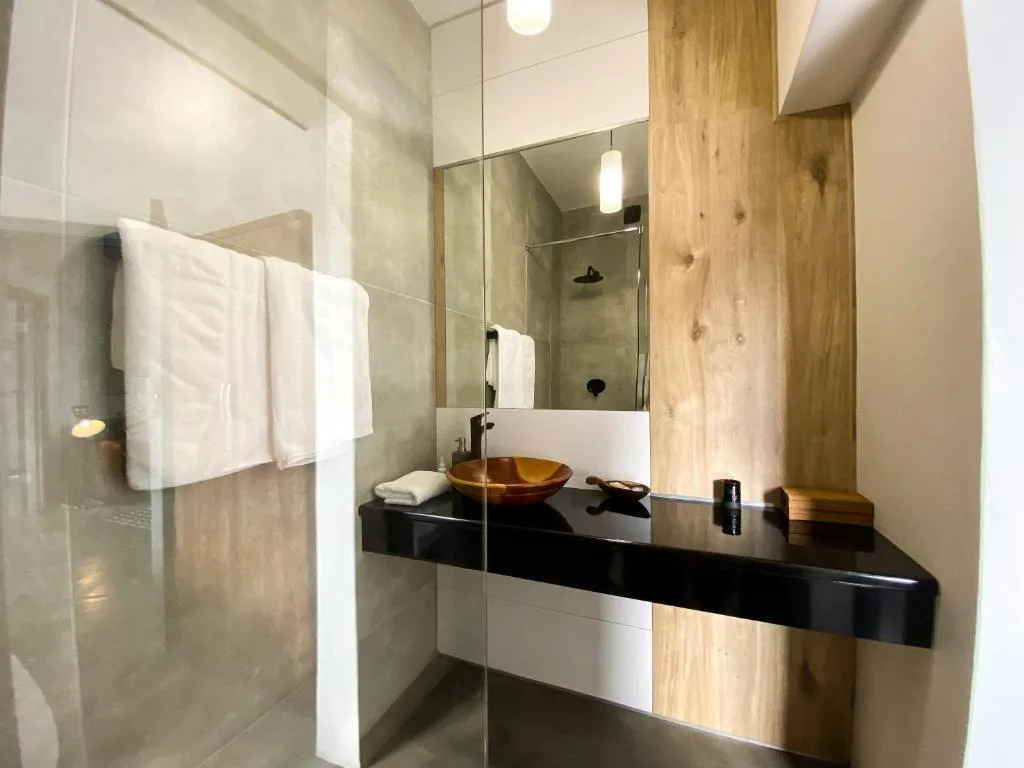 Modern bathroom with black vanity, vessel sink, and walk-in shower enclosure