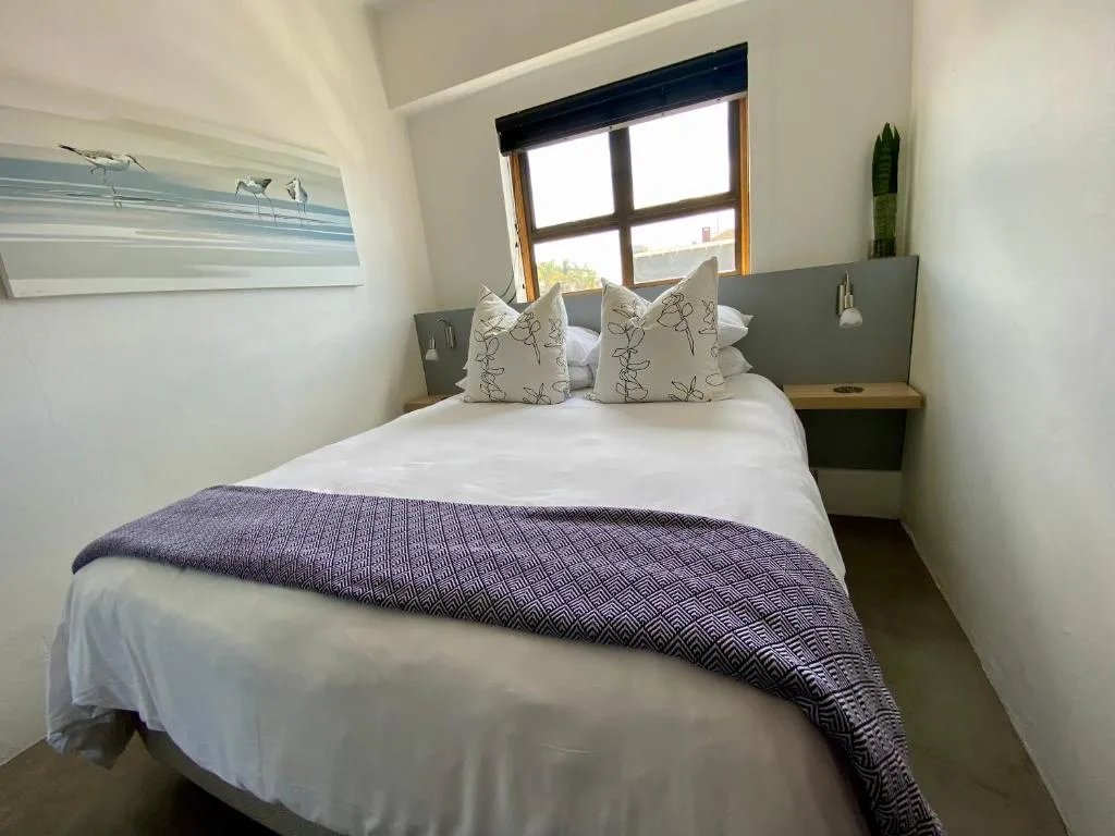 Modern bedroom with queen bed, decorative pillows, and bright window