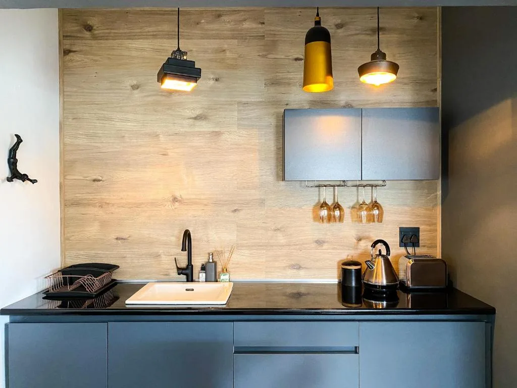 Modern kitchen with blue cabinetry, wooden backsplash, pendant lights, sink
