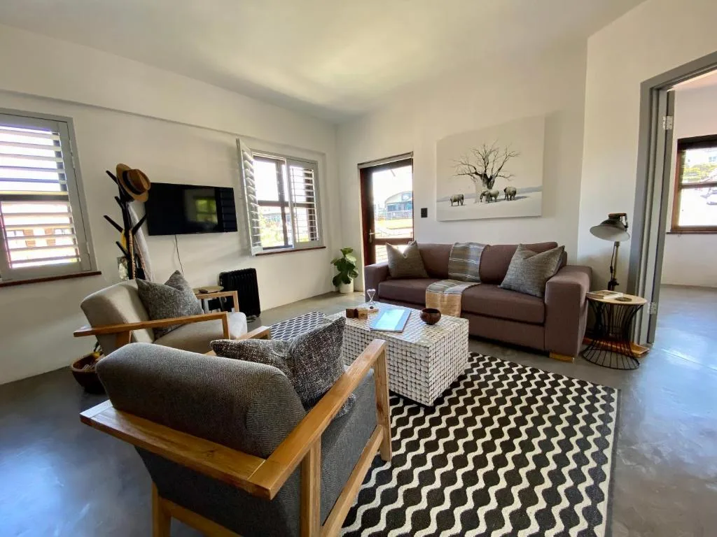 Spacious living room with grey sofas, wooden armchairs, patterned rug