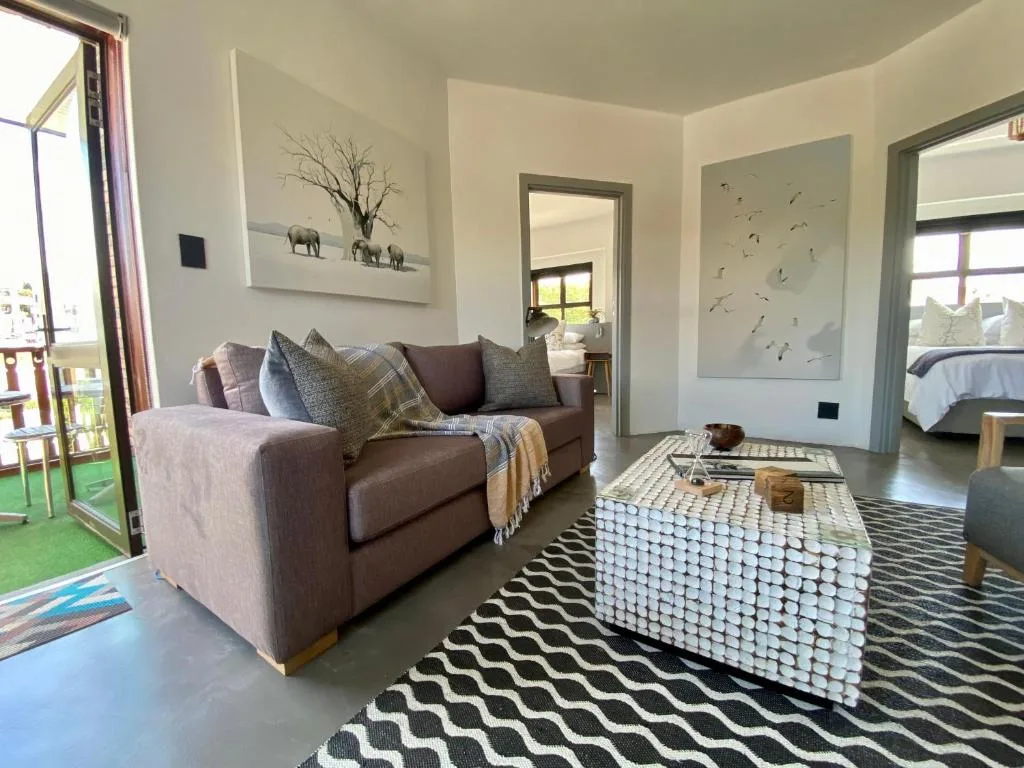 Contemporary lounge with brown sofa, patterned rug, and natural light from windows