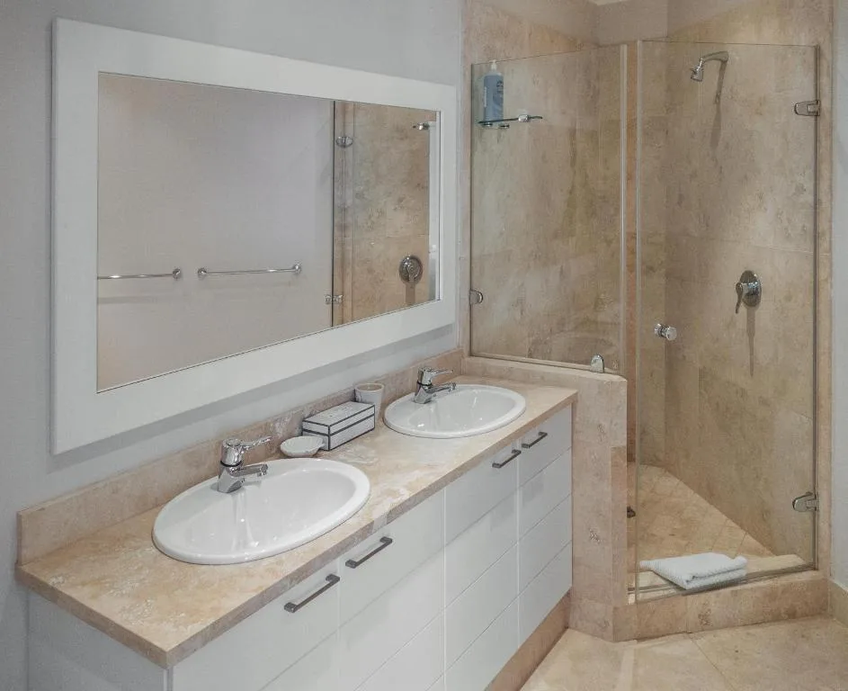 Modern bathroom with dual sinks, large mirror, and walk-in shower enclosure