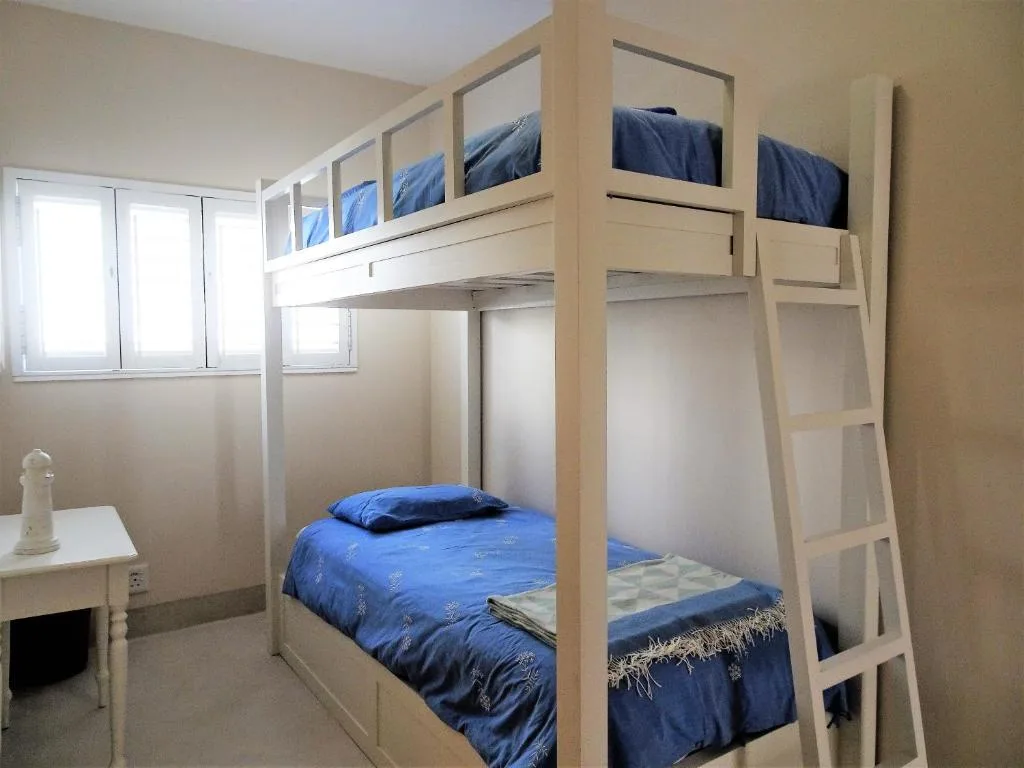 Bright bedroom with wooden bunk beds and blue bedding throughout