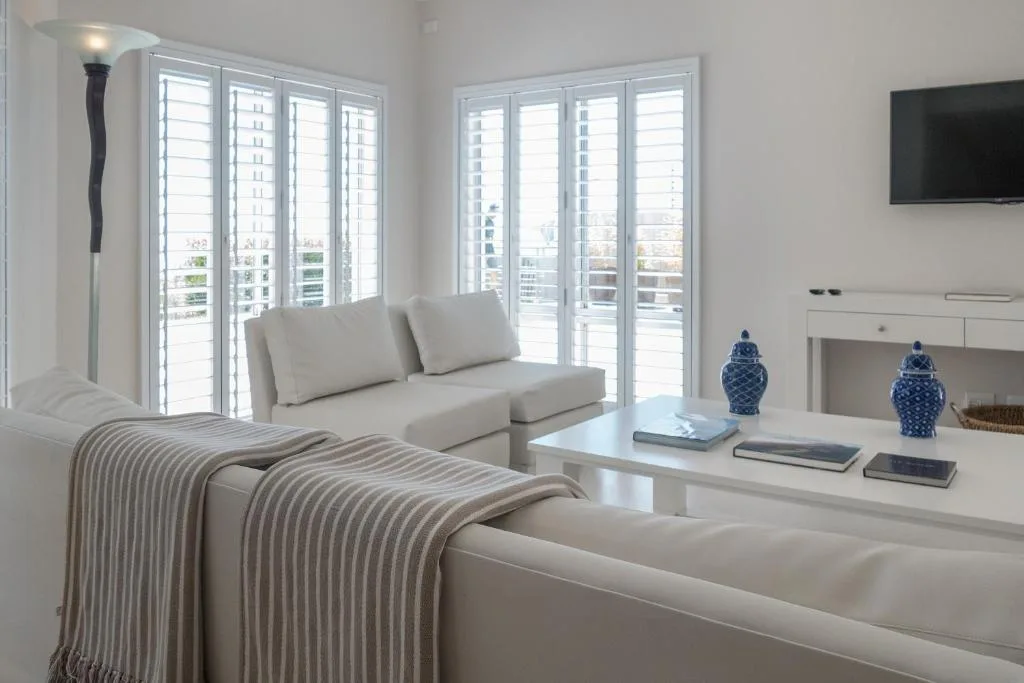Bright bedroom with bed, lounge seating, and floor-to-ceiling windows overlooking the ocean