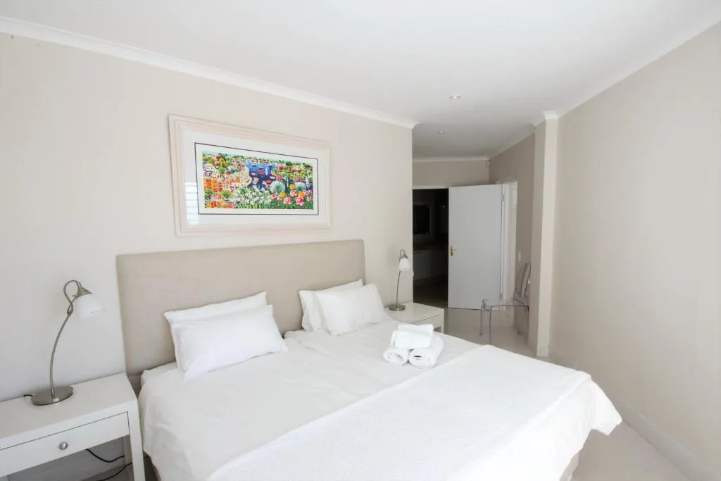 Spacious bedroom with double bed, neutral bedding, and framed artwork on wall