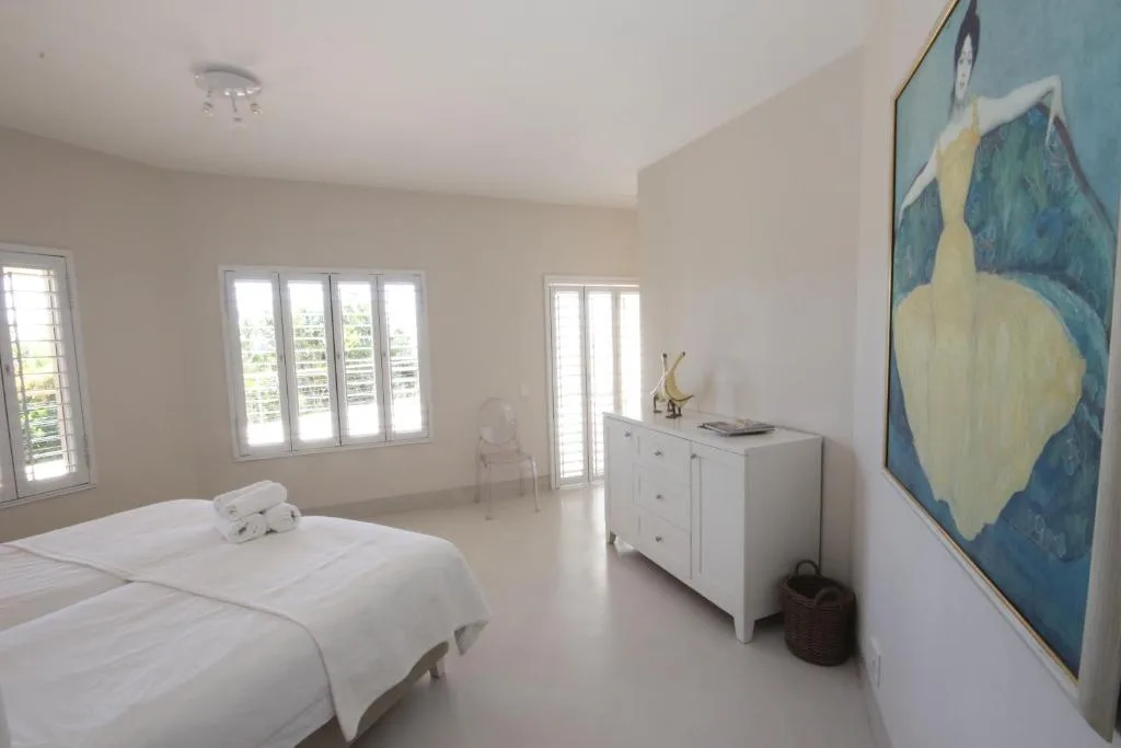 Bright, spacious bedroom with twin beds and large windows overlooking garden views
